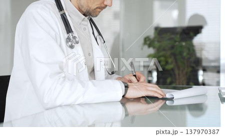 Doctor man writing prescription, consulting patient, and working at clinic office, providing healthcare and medicine. Medicine, health care and science concept Doctor man writing prescription, consulting patient, and working at clinic office, providing healthcare and medicine. Medicine, health care and science concept 137970387