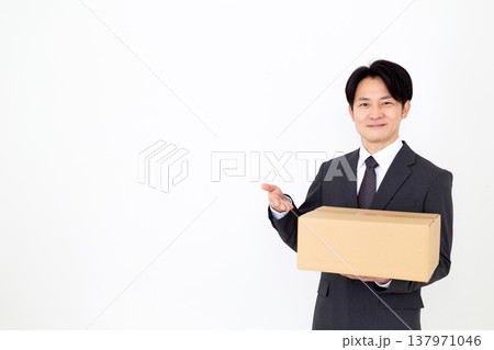 段ボールの荷物を持つミドル男性ビジネスマン 段ボールの荷物を持つミドル男性ビジネスマン 137971046