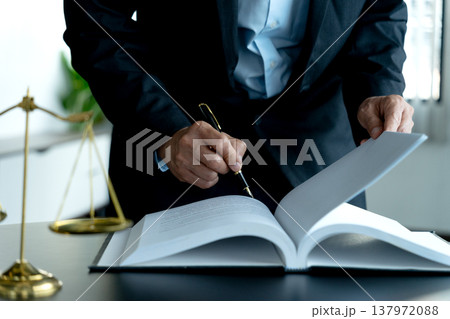 The lawyer is standing and looking at the papers prepared on the table The lawyer is standing and looking at the papers prepared on the table 137972088