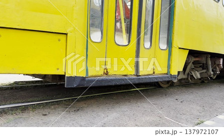 Close up of bright yellow tram passing the camera on city tracks. The moving wheels create a sense of speed and rhythm, capturing the dynamic motion of urban transport in action. Slow motion Close up of bright yellow tram passing the camera on city tracks. The moving wheels create a sense of speed and rhythm, capturing the dynamic motion of urban transport in action. Slow motion 137972107