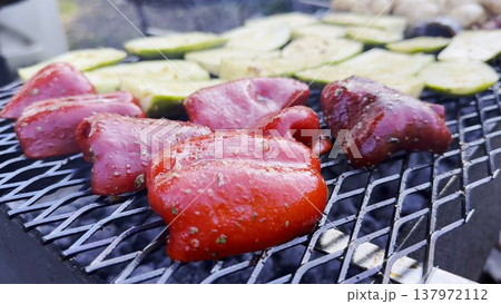 Vegetables roasting on home grill over open heat at summer day. Smoke rises gently as meal cook developing lightly charred surface. The focus on grilling process, texture and appetizing appearance 137972112