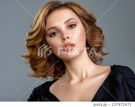Beautiful brown haired with stylish short hairstyle. Woman with a  curly hair. Beautiful young woman with freckles on face.  Closeup portrait of an attractive girl  with a brown makeup. 137972471