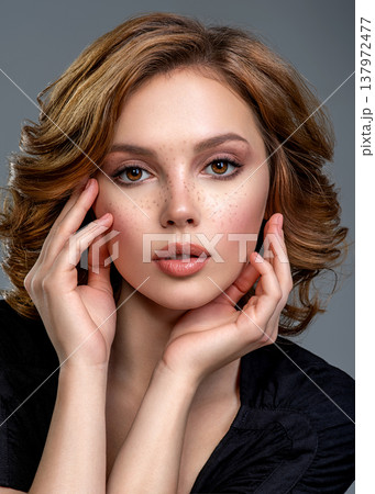 Beautiful brown haired with stylish short hairstyle. Woman with a  curly hair. Beautiful young woman with freckles on face.  Closeup portrait of an attractive girl  with a brown makeup. 137972477