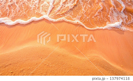 Golden sunlight reflects beautifully on the tranquil shoreline as gentle waves caress the sandy beach creating a soothing and peaceful scene. 137974118