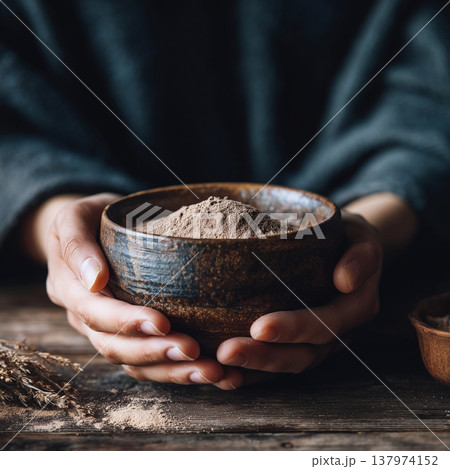 Hands Cradling Rustic Ceramic Bowl with Natural Herbal Powder 137974152