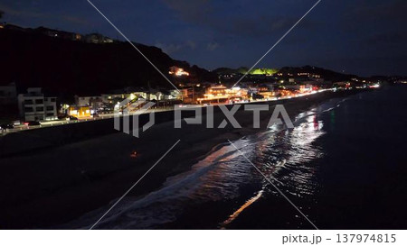 夜の七里ヶ浜海岸。ライトアップされたレストランと波の煌めき(ドローン撮影) 夜の七里ヶ浜海岸。ライトアップされたレストランと波の煌めき(ドローン撮影) 137974815