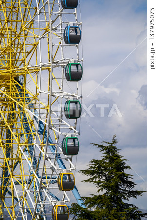 Colorful ferris wheel gondolas against cloudy sky Colorful ferris wheel gondolas against cloudy sky 137975075