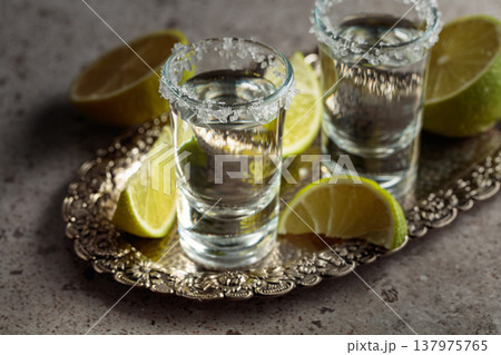 Tequila with salt and lime slices on a silver tray. Tequila with salt and lime slices on a silver tray. 137975765