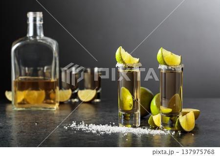 Tequila shots with salt and lime slices on a black stone table. 137975768