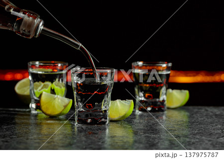 Strong alcoholic drink and lime slices on a black background. 137975787