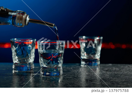 Vodka is poured into a shot glasses. 137975788