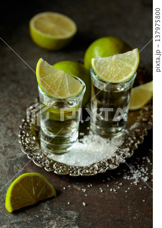 Tequila with salt and lime slices on a silver tray. 137975800