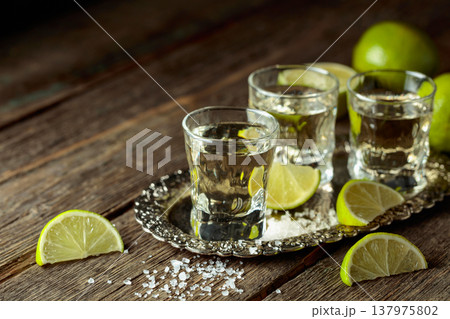 Tequila with salt and lime slices on a silver tray. Tequila with salt and lime slices on a silver tray. 137975802