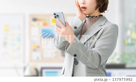 スマートフォンを見て驚く女性・ビジネスウーマン 137975992