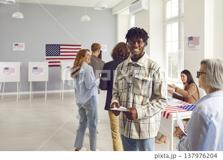 Happy young African American man is standing in queue at election station in USA 137976204