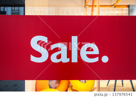 Red sale sign displayed on a retail store window 137976541