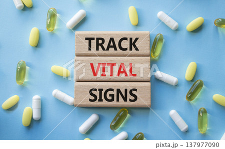 TRACK VITAL SIGNS symbol. Concept words TRACK VITAL SIGNS on wooden blocks. Beautiful blue background with pills. Healthcare and TRACK VITAL SIGNS concept. Copy space. 137977090
