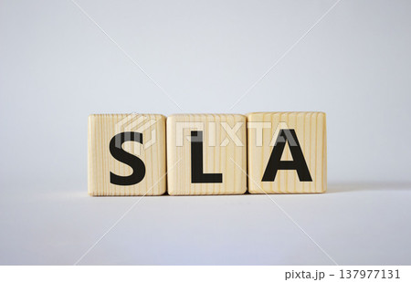 SLA - Service Level Agreement. Wooden cubes with word SLA. Beautiful white background. Business and Service Level Agreement concept. Copy space. 137977131