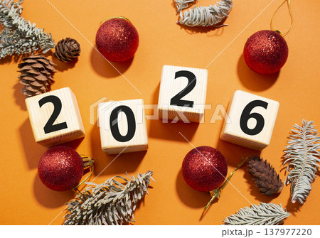 2026 New Year symbol. Wooden cubes with words 2026. Beautiful orange background with Christmas balls and pine cones. Copy space. Business and 2026 happy new year concept 2026 New Year symbol. Wooden cubes with words 2026. Beautiful orange background with Christmas balls and pine cones. Copy space. Business and 2026 happy new year concept 137977220