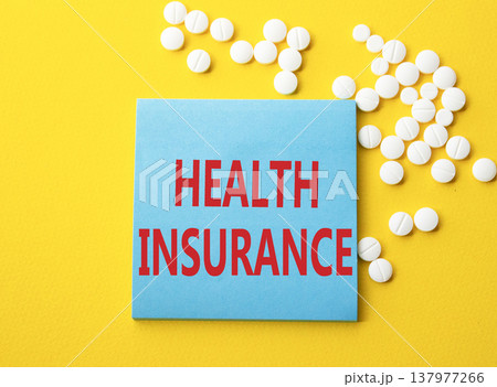 Health Insurance symbol. Concept word Health Insurance on blue note. Beautiful yellow background with pills. Medicine and Health Insurance concept. Copy space 137977266