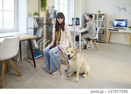 Smiling owner with Labrador in veterinary clinic, vet reviews X ray in background Smiling owner with Labrador in veterinary clinic, vet reviews X ray in background 137977306