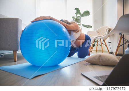 Pregnant woman exercising with fitness ball at home Pregnant woman exercising with fitness ball at home 137977472
