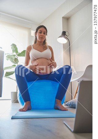 Pregnant woman exercising with fitness ball at home Pregnant woman exercising with fitness ball at home 137977478
