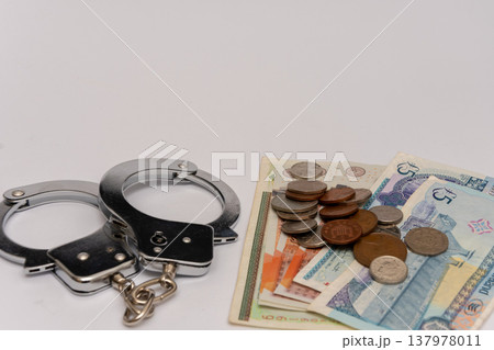 Handcuffs and British pounds reflecting confiscation fines and financial sanctions Handcuffs and British pounds reflecting confiscation fines and financial sanctions 137978011