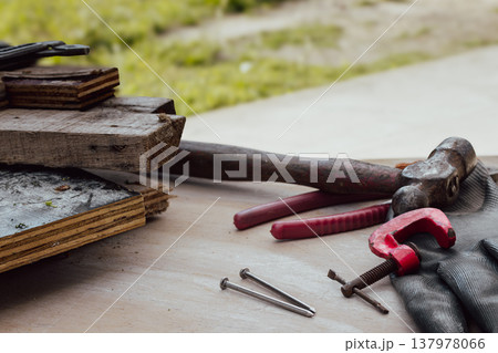 Carpenter's tools, including a hammer, clamp, and nails, on a wooden workbench. Tools and equipment for home maintenance 137978066