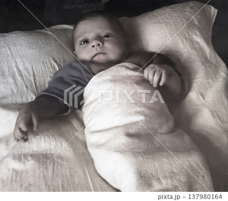 A vintage portrait of a little boy in a loose shirt and diaper, lying on a bed. Retro photo from 1959. 137980164