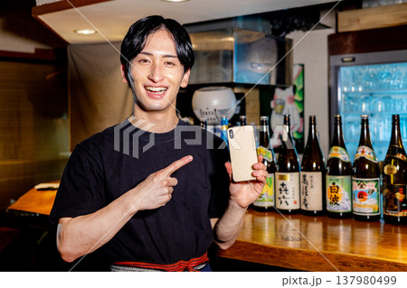 居酒屋で働く男性　スマホ 137980499