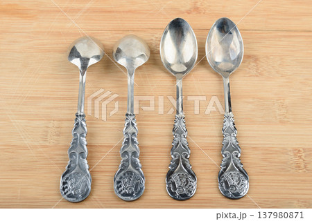 Four elegant vintage teaspoons arranged in a row on a wooden stand. 137980871