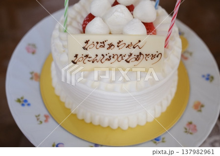 おばあちゃんのお誕生日祝いの蝋燭つきホールケーキ おばあちゃんのお誕生日祝いの蝋燭つきホールケーキ 137982961