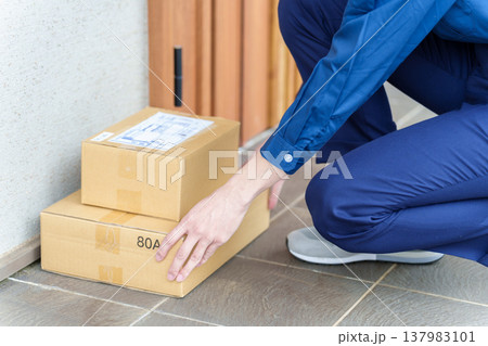 玄関に荷物を置き配をする配達員 玄関に荷物を置き配をする配達員 137983101