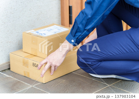 玄関に荷物を置き配をする配達員 137983104