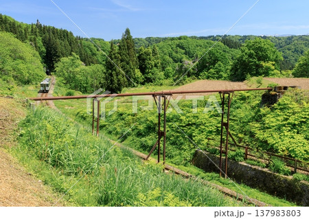 田畑を支えてきた錆びた送水管を見上げて走る飯山線の気動車 田畑を支えてきた錆びた送水管を見上げて走る飯山線の気動車 137983803