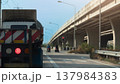 Rear side of truck car with turn on brake light. Stop by traffic red light control with two motorcycles parked right in front of the intersection. Concrete overpass bridge on the side of the road. 137984383