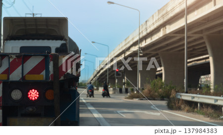 Rear side of truck car with turn on brake light. Stop by traffic red light control with two motorcycles parked right in front of the intersection. Concrete overpass bridge on the side of the road. Rear side of truck car with turn on brake light. Stop by traffic red light control with two motorcycles parked right in front of the intersection. Concrete overpass bridge on the side of the road. 137984383