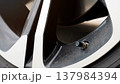 Detailed showing a black rubber tire valve stem with its protective cap. Essential component allows for air inflation and pressure monitoring to ensure vehicle safety and performance. 137984394
