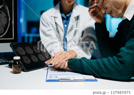 Female doctor comforting stressed male patient during medical consultation. Brain MRI scan, mental health diagnosis, healthcare support and modern medical technology. Female doctor comforting stressed male patient during medical consultation. Brain MRI scan, mental health diagnosis, healthcare support and modern medical technology. 137985975