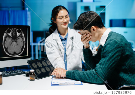 Female doctor comforting stressed male patient during medical consultation. Brain MRI scan, mental health diagnosis, healthcare support and modern medical technology. 137985976