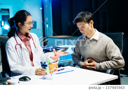 Doctor explains digestive system using anatomy model during consultation with patient suffering abdominal pain. Gastroenterology, diagnosis, treatment, healthcare concept. 137985983