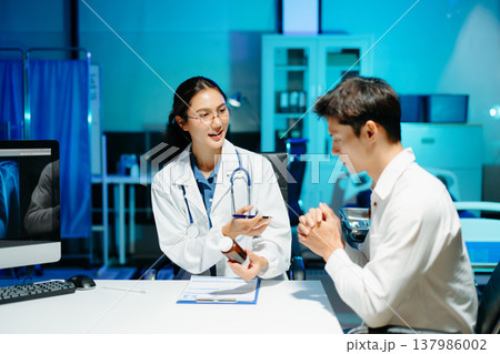 Asian female doctor consulting patient, taking medical history and explaining treatment in modern clinic 137986002