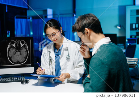 Female doctor reviewing brain MRI and notes during medical consultation with stressed male patient. Neurology diagnosis, mental health care and modern healthcare technology. Female doctor reviewing brain MRI and notes during medical consultation with stressed male patient. Neurology diagnosis, mental health care and modern healthcare technology. 137986011