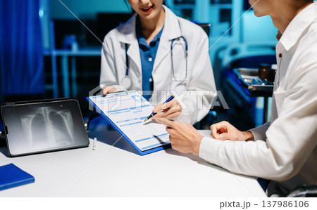 Professional female doctor explaining chest X-ray results to patient in modern clinic, medical consultation, radiology, healthcare, and diagnosis concept. Professional female doctor explaining chest X-ray results to patient in modern clinic, medical consultation, radiology, healthcare, and diagnosis concept. 137986106