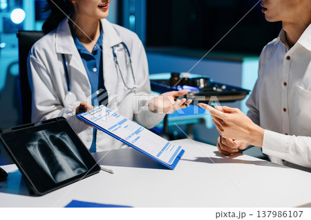 Asian doctor consulting patient in modern hospital office, explaining medical report and providing professional healthcare advice with trust Asian doctor consulting patient in modern hospital office, explaining medical report and providing professional healthcare advice with trust 137986107