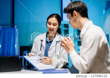 Asian doctor consulting patient in modern hospital office, explaining medical results and giving professional healthcare advice with friendly communication. Asian doctor consulting patient in modern hospital office, explaining medical results and giving professional healthcare advice with friendly communication. 137986110