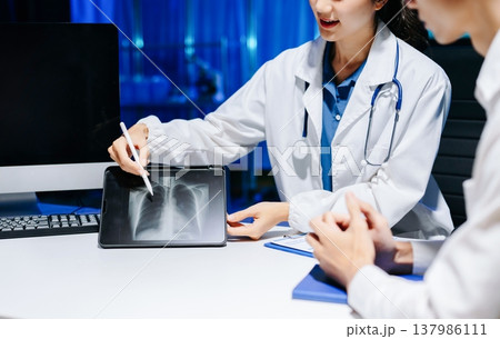 Asian doctor consulting patient in modern hospital office, explaining medical report and providing professional healthcare advice with trust 137986111