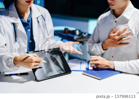 Asian doctor consulting patient in modern hospital office, explaining medical report and providing professional healthcare advice with trust Asian doctor consulting patient in modern hospital office, explaining medical report and providing professional healthcare advice with trust 137986113