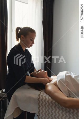 Woman receiving relaxing professional neck and shoulder massage therapy. Client enjoying rejuvenating massage treatment in tranquil spa environment Woman receiving relaxing professional neck and shoulder massage therapy. Client enjoying rejuvenating massage treatment in tranquil spa environment 137986234